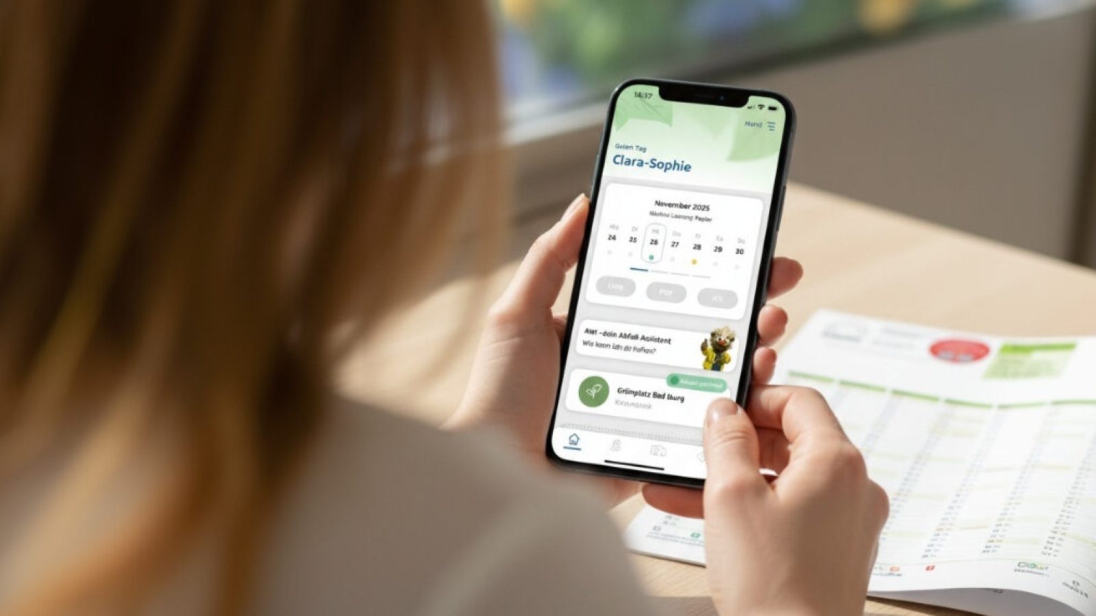 Person, die ein Smartphone mit einer App zur Abfallentsorgung in der Hand hält, während sie auf einen Tisch schaut.