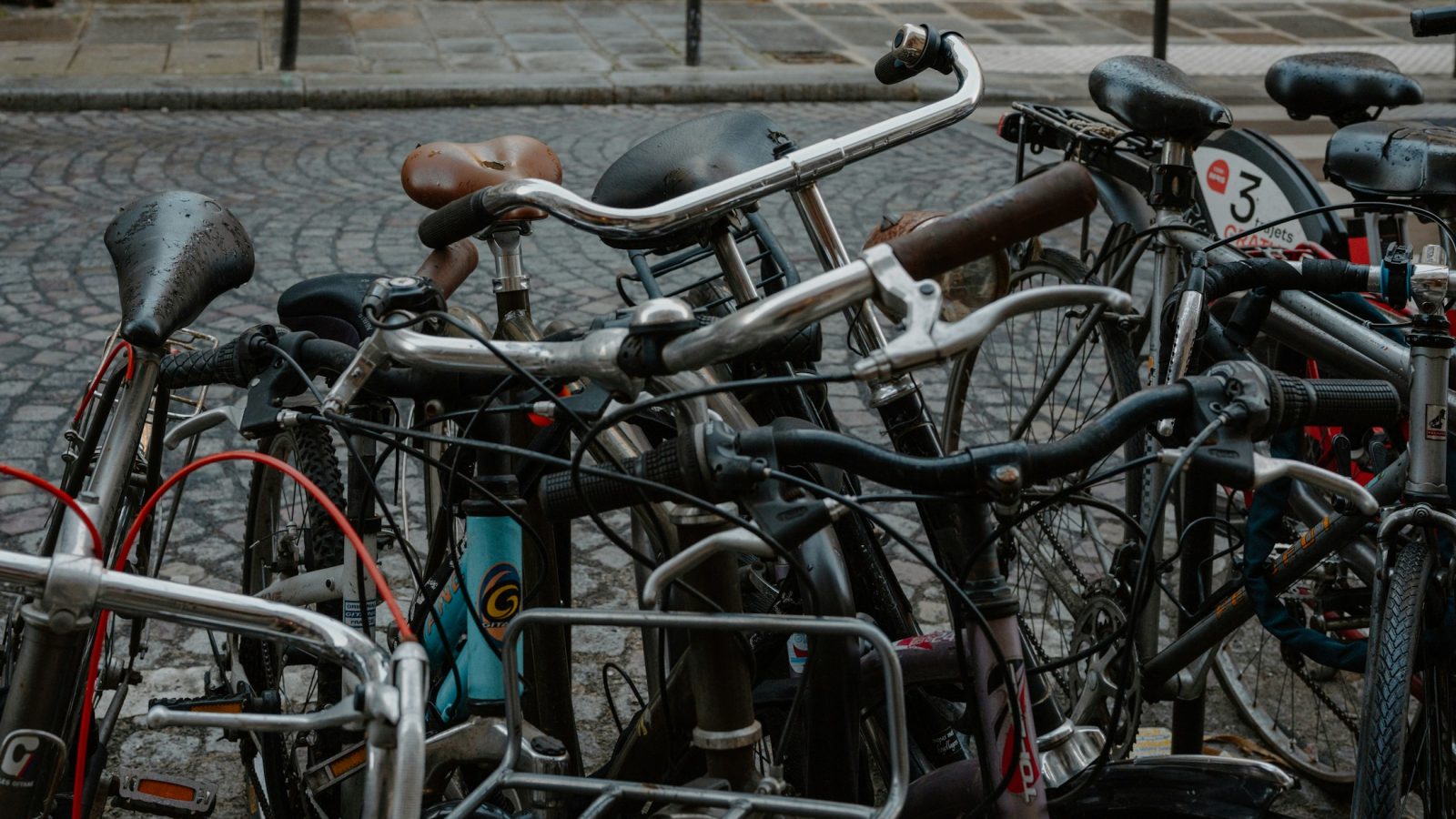 Mehrere abgestellte Fahrräder stehen auf einer gepflasterten Straße