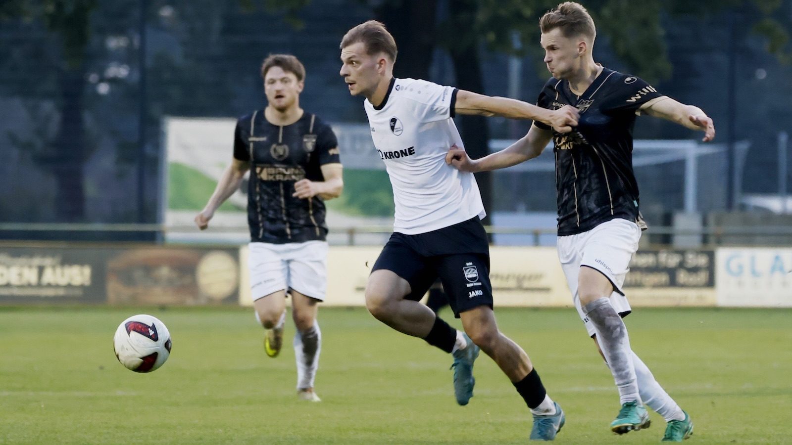 Adrian Lenz vom SC Spelle-Venhaus im weißen Trikot setzt sich im Zweikampf gegen einen Gegenspieler in Schwarz durch