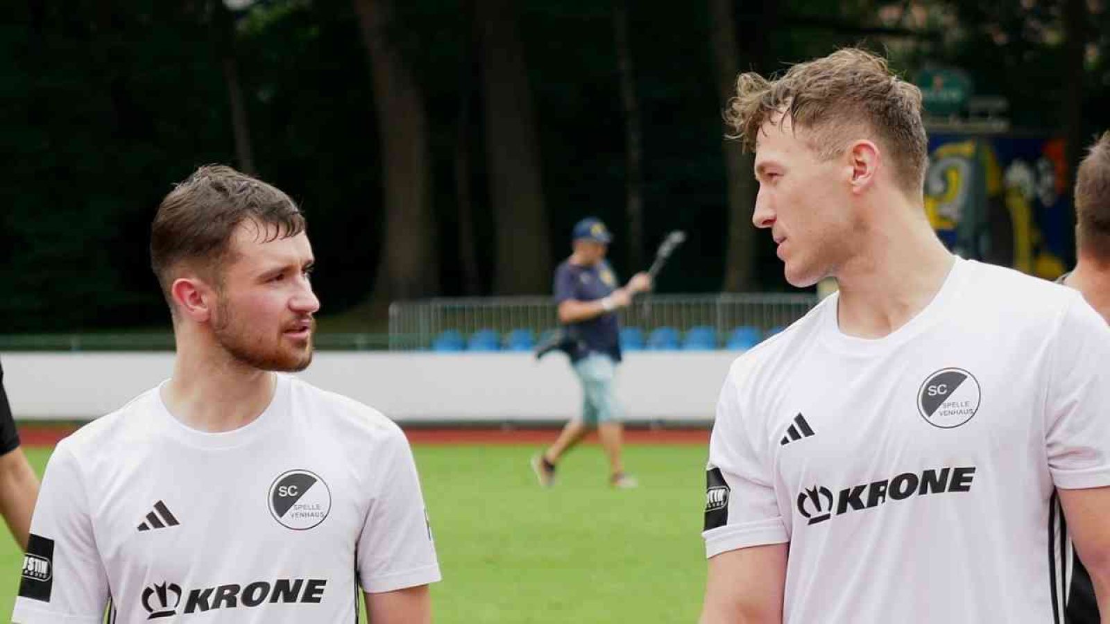 Zwei Fußballspieler im Gespräch auf dem Spielfeld im weißen Trikot des SC Spelle Venhaus.