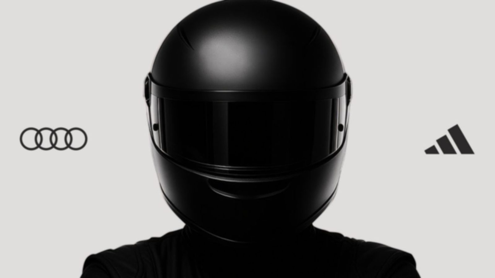 Schwarzer Helm im Vordergrund, Audi- und Adidas-Logos auf grauem Hintergrund. Futuristisches Design, minimalistisch.