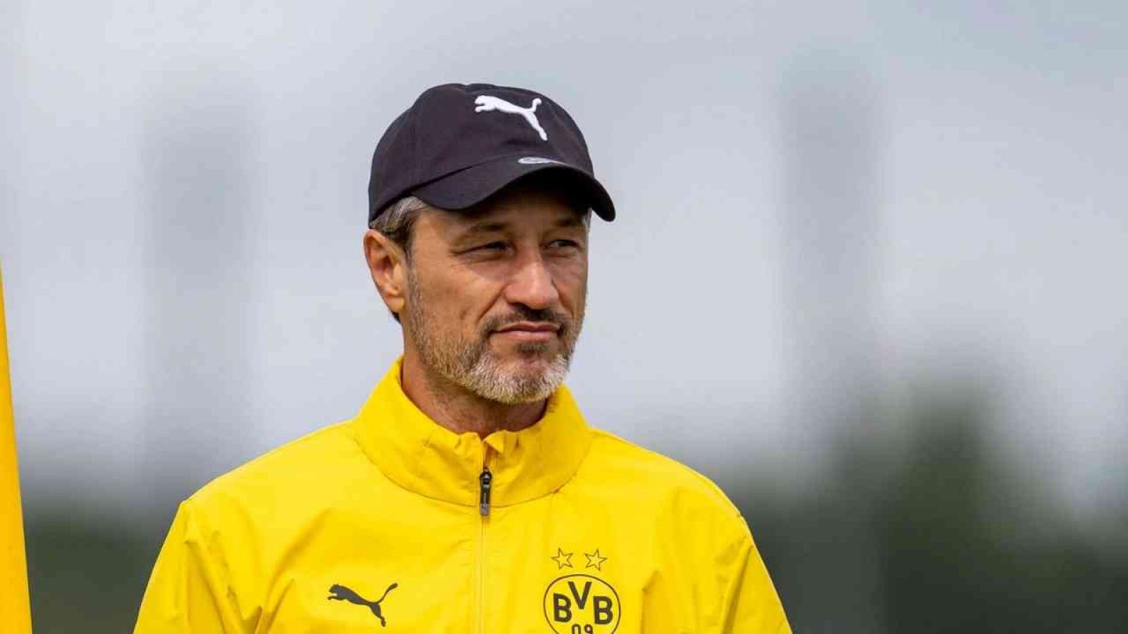 Trainer im gelben BVB-Jacke und schwarzer Mütze beim Fußballtraining.