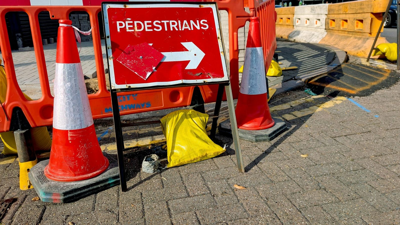 Absperrbaken und Hinweisschild markieren eine Baustelle auf einem Weg