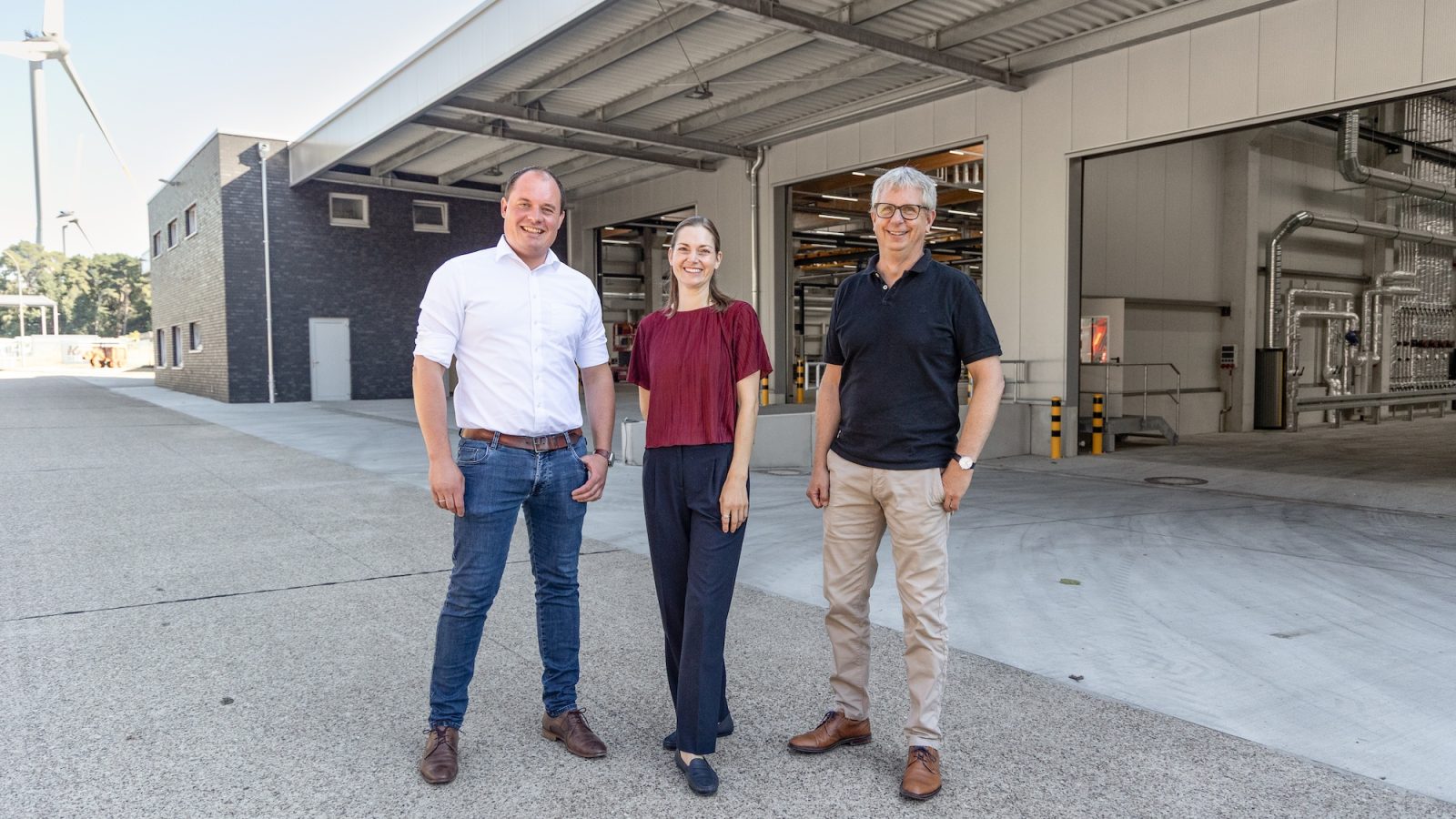 Robin Krampe, Eliza Diekmann-Cloppenburg und Philipp Hänsel vor der neuen Fertigungshalle von Krampe Fahrzeugbau