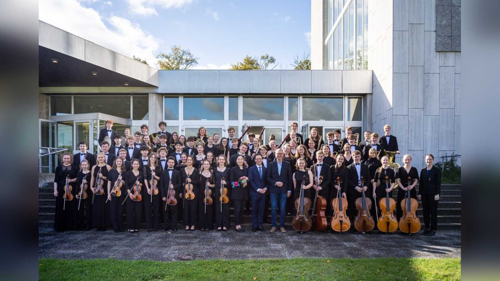 Die Musikerinnen und Musiker des Niedersächsischen Jugendsinfonieorchesters mit ihren Instrumenten vor einem Konzerthaus