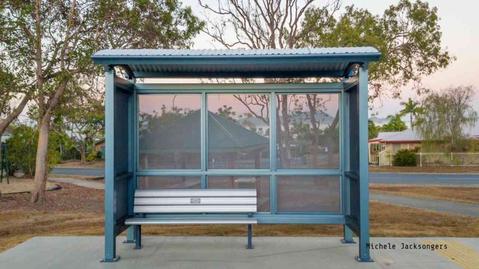 Moderne Bushaltestelle mit einem überdachten Wartebereich und einer Sitzbank aus Metall.