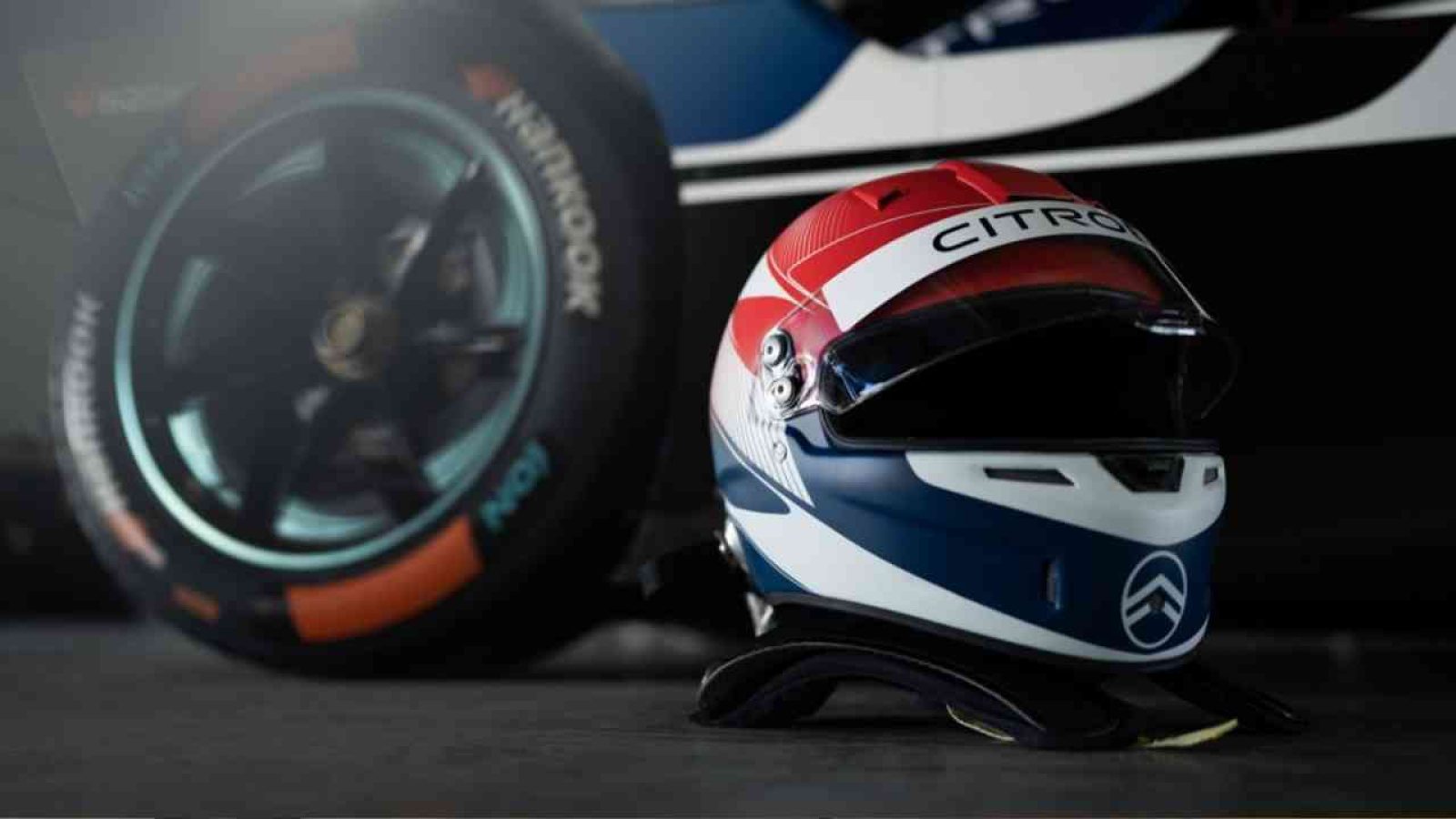 Rennhelm mit Citroen-Logo in Rot, Weiß und Blau, platziert neben einem Formel-E-Rad.