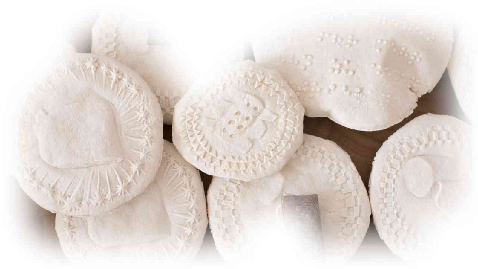 Weiße, runde Objekte mit verschiedenen strukturierten Mustern und Prägungen auf der Oberfläche.