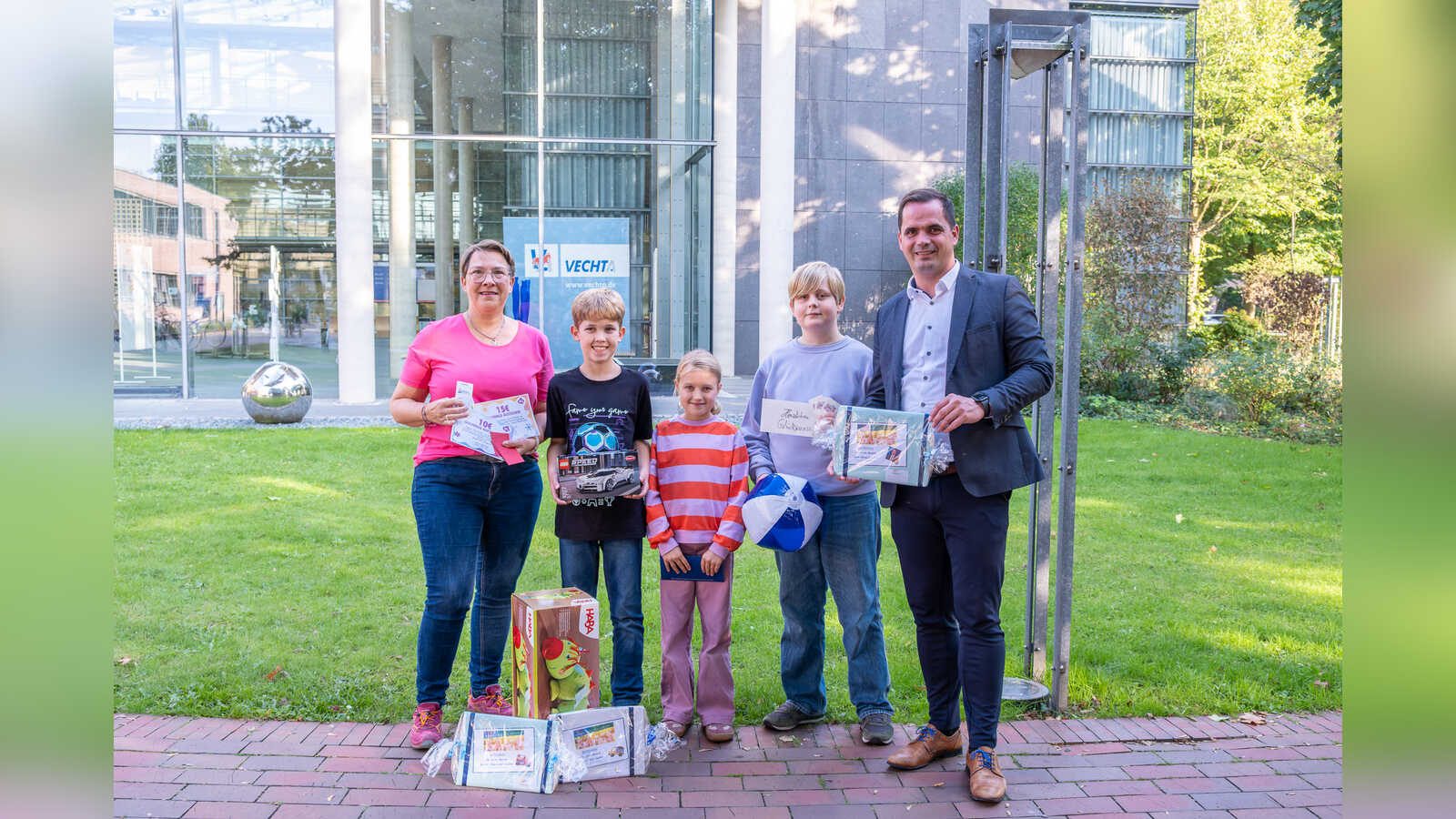 Bürgermeister Kristian Kater und Andrea Schlärmann vom Familienbüro mit drei Kindern bei der Übergabe der Hauptgewinne im Rathaus Vechta