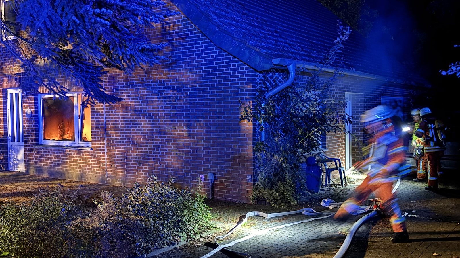 Feuerwehrfahrzeuge mit Blaulicht auf einer Straße in Werlte während des Löscheinsatzes bei Nacht