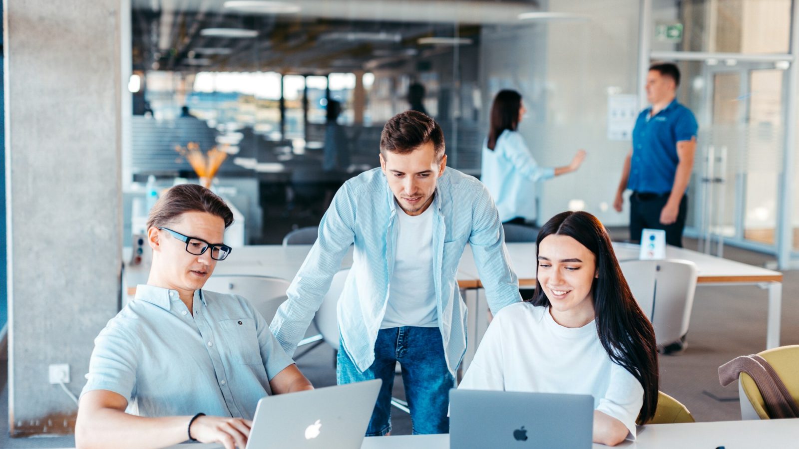 Mehrere Gründerinnen und Gründer sitzen mit Laptops zusammen und besprechen einen Businessplan