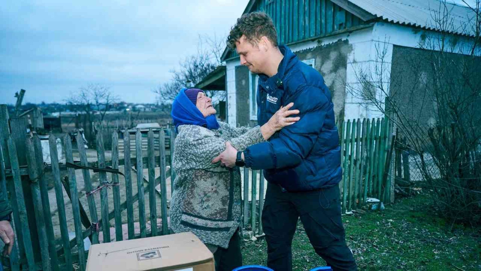 Mann hilft älterer Frau in der Ukraine während der Wintermonate mit Lebensmitteln und Unterstützung.