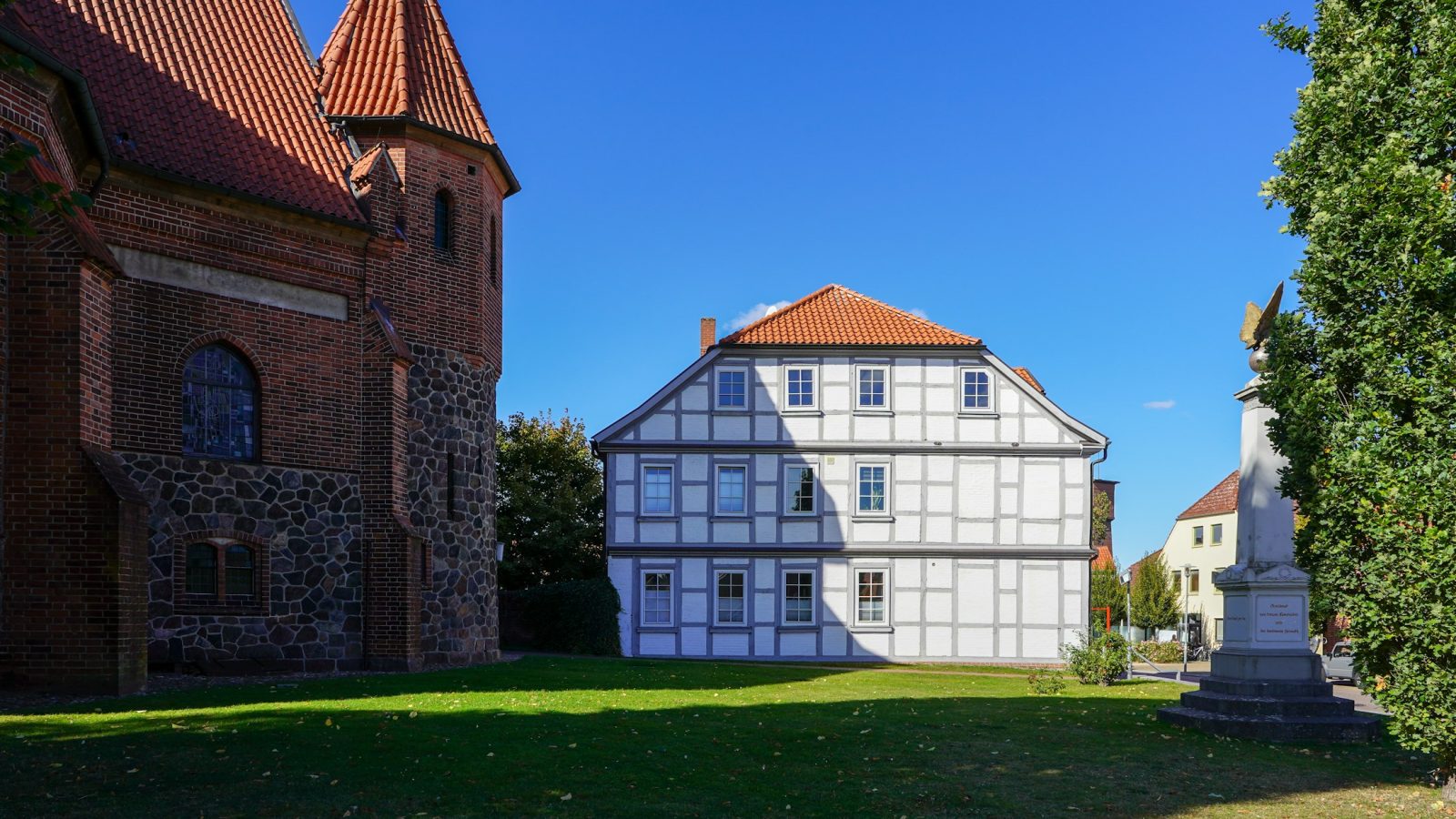 Historisches Fachwerkhaus neben einer Backsteinkirche (Symbolbild)