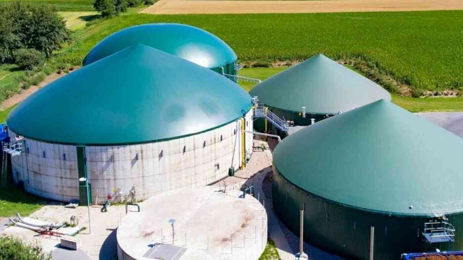 Grüne Biogasanlage in ländlicher Umgebung mit Silos, die erneuerbare Energie produzieren.