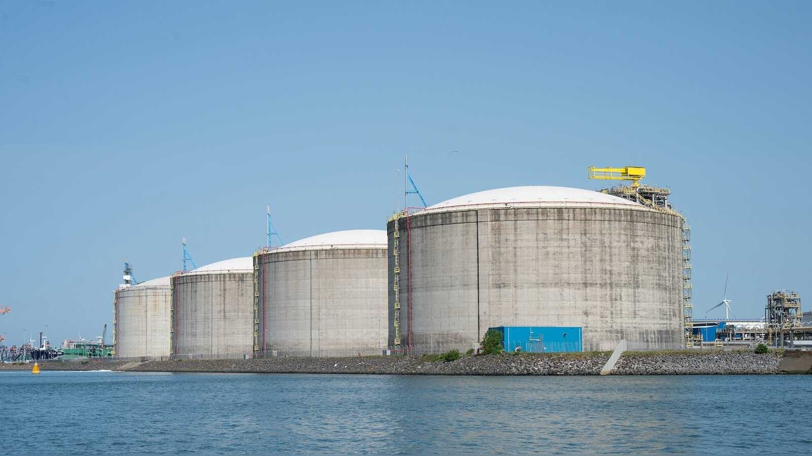 Große Industrietanks am Wasser unter klarem Himmel