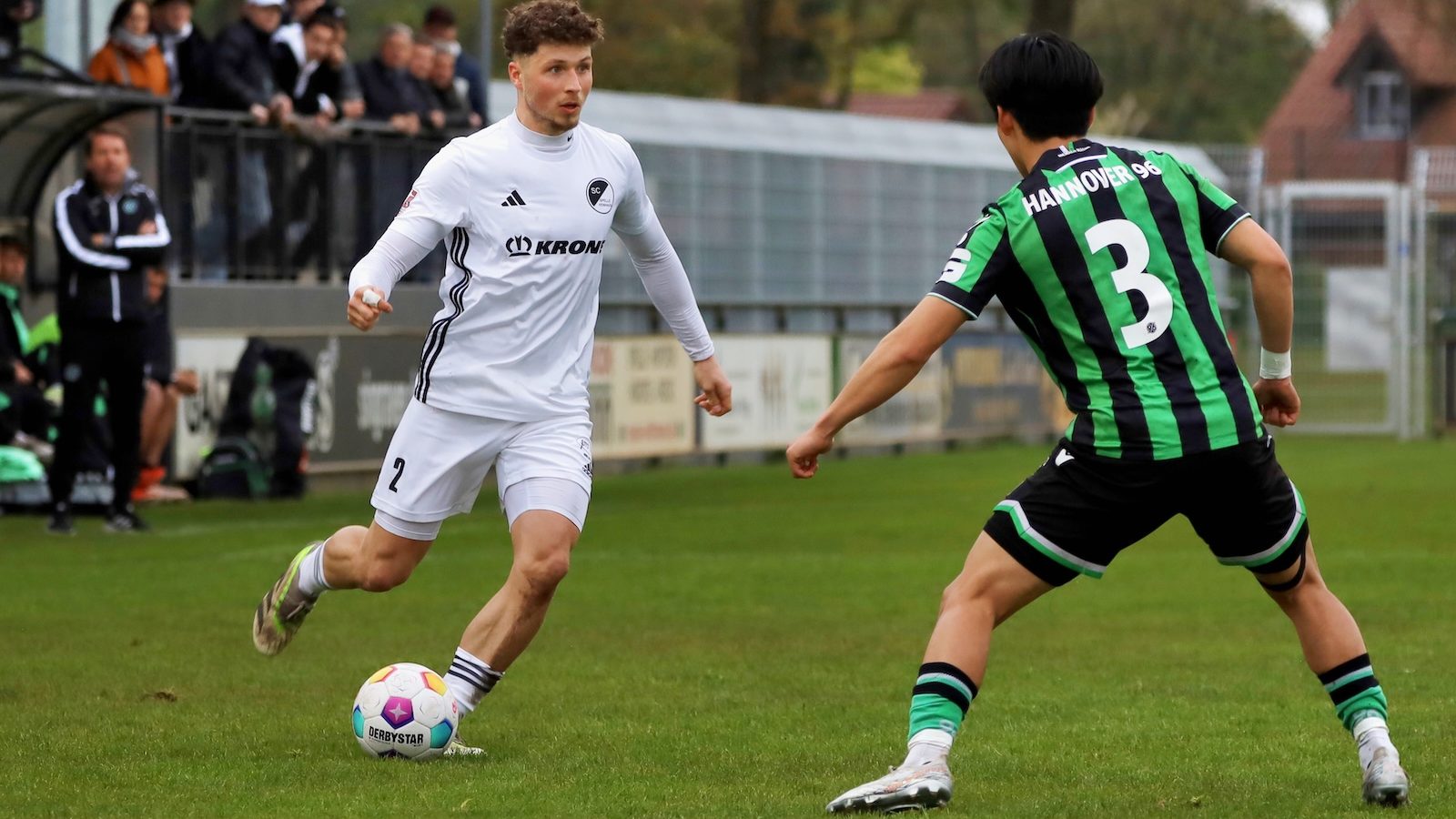 Jonas Tepper im weißen Trikot des SC Spelle-Venhaus im Zweikampf mit einem Spieler von Hannover 96 II