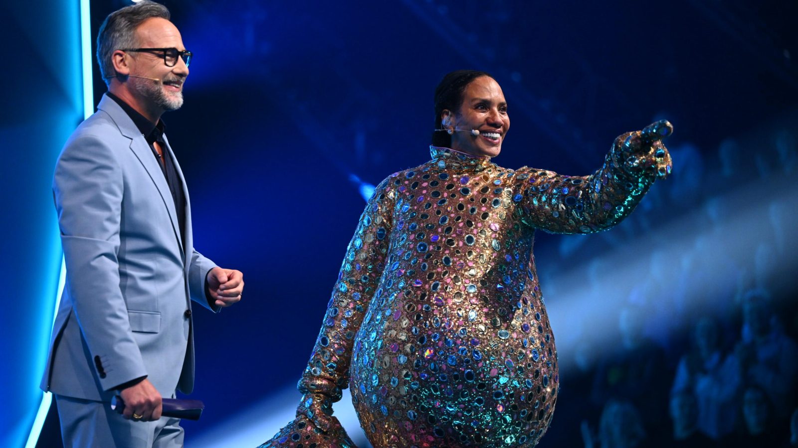 Titel: The Masked Singer;
Staffel: 12;
Folge: 1;
Person: Smiley; Barbara Becker; Matthias Opdenhövel;
Copyright: Joyn/Willi Weber;
Fotograf: Willi Weber;
Bildredakteur: Nadine Vaders;
Dateiname: 3300236.JPG;
Rechtehinweis: Dieses Bild darf honorarfrei für redaktionelle Zwecke und nur im Rahmen der Programmankündigung verwendet werden. Andere Veröffentlichungen sind nur nach Rücksprache und ausdrücklicher Genehmigung der Seven.One Entertainment Group GmbH möglich. Nicht für EPG! Verwendung nur mit vollständigem Copyrightvermerk. Das Foto darf nicht verändert, bearbeitet und nur im Ganzen verwendet werden. Es darf nicht archiviert werden. Es darf nicht an Dritte weitergeleitet werden. Aneinanderreihung/Zusammenlegung/Kopplung von Bildern zum Zweck der Erstellung von Slide-Shows o.ä. nicht gestattet; Verbindung/Einfügen/Anfügen von Werbung nicht gestattet. Das Bild kann KI generierte Elemente enthalten.
Bei Fragen: foto@seven.one
Voraussetzung für die Verwendung dieser Programmdaten ist die Zustimmung zu den Allgemeinen Geschäftsbedingungen der Presselounges der Sender der Seven.One Entertainment Group GmbH. / Weiterer Text über ots und www.presseportal.de/nr/25171 / Die Verwendung dieses Bildes für redaktionelle Zwecke ist unter Beachtung aller mitgeteilten Nutzungsbedingungen zulässig und dann auch honorarfrei. Veröffentlichung ausschließlich mit Bildrechte-Hinweis.