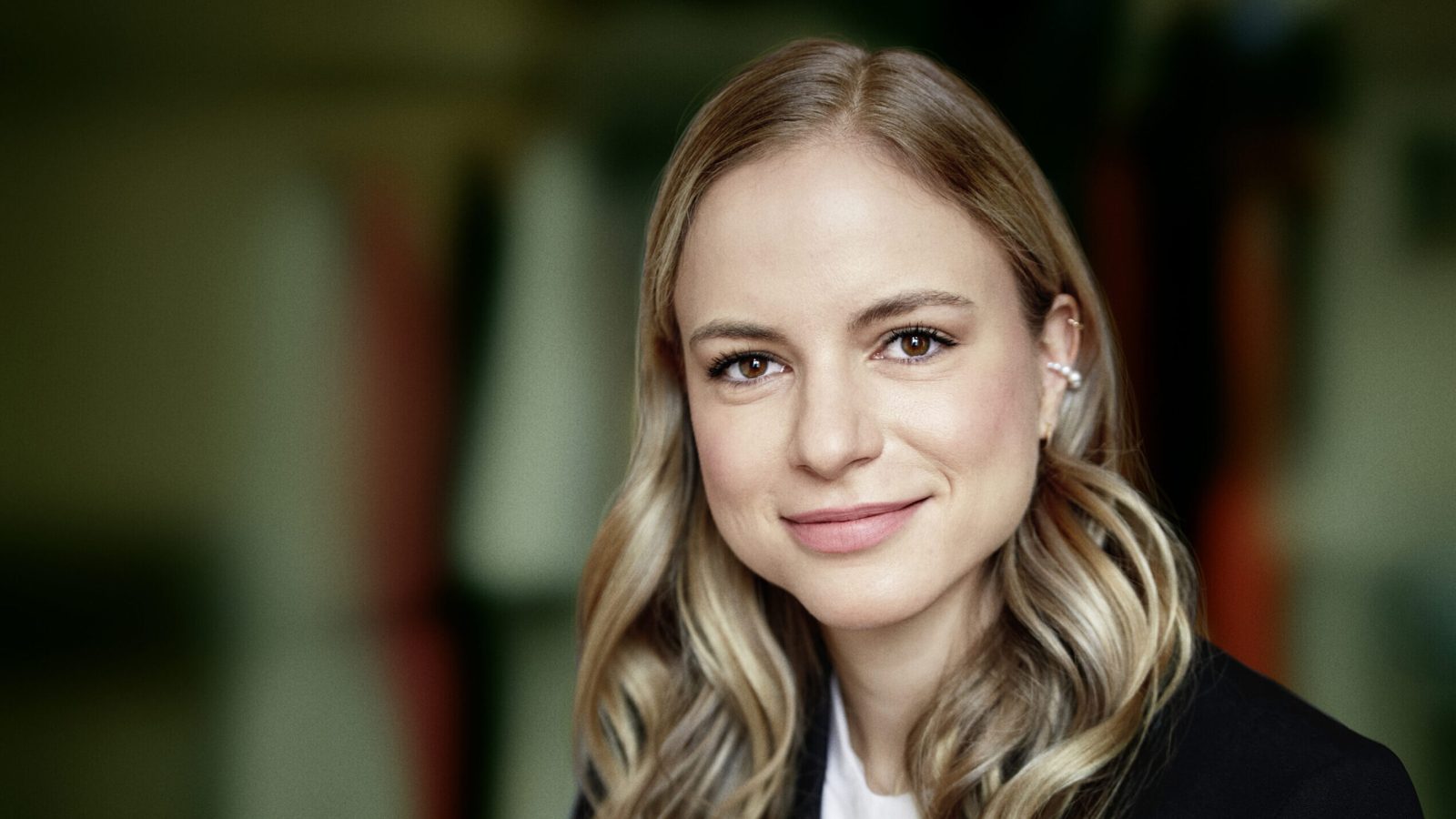 Porträt von Julia Engelmann mit langen, welligen Haaren und einem freundlichen Lächeln, in einem professionellen Outfit.