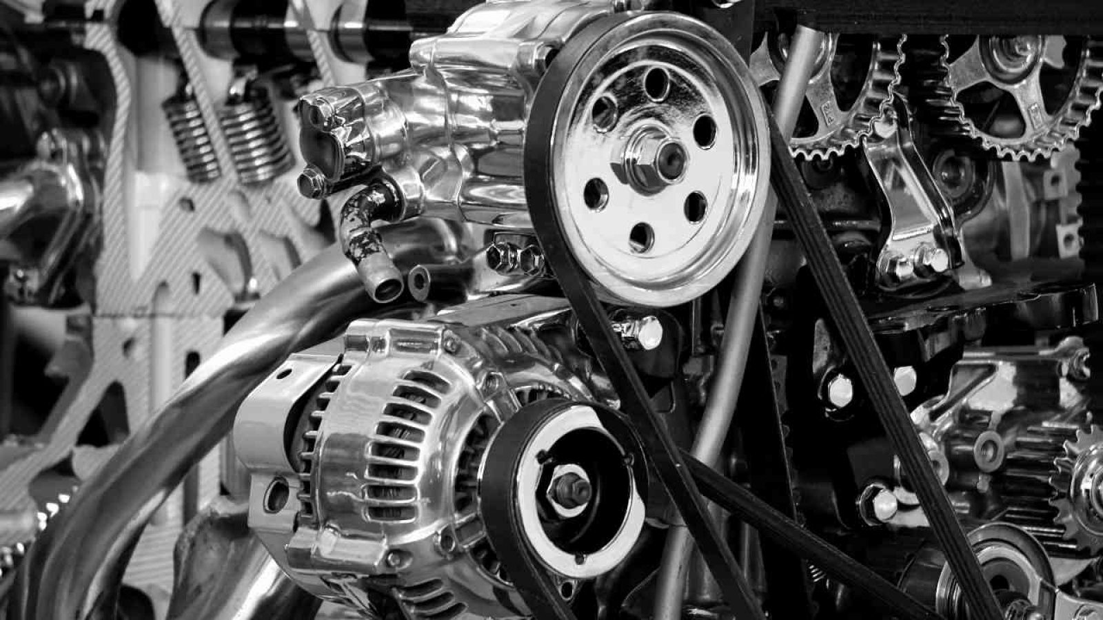 Nahaufnahme eines komplexen Automotormotors mit Zahnrädern und Riemen in Schwarz-Weiß.