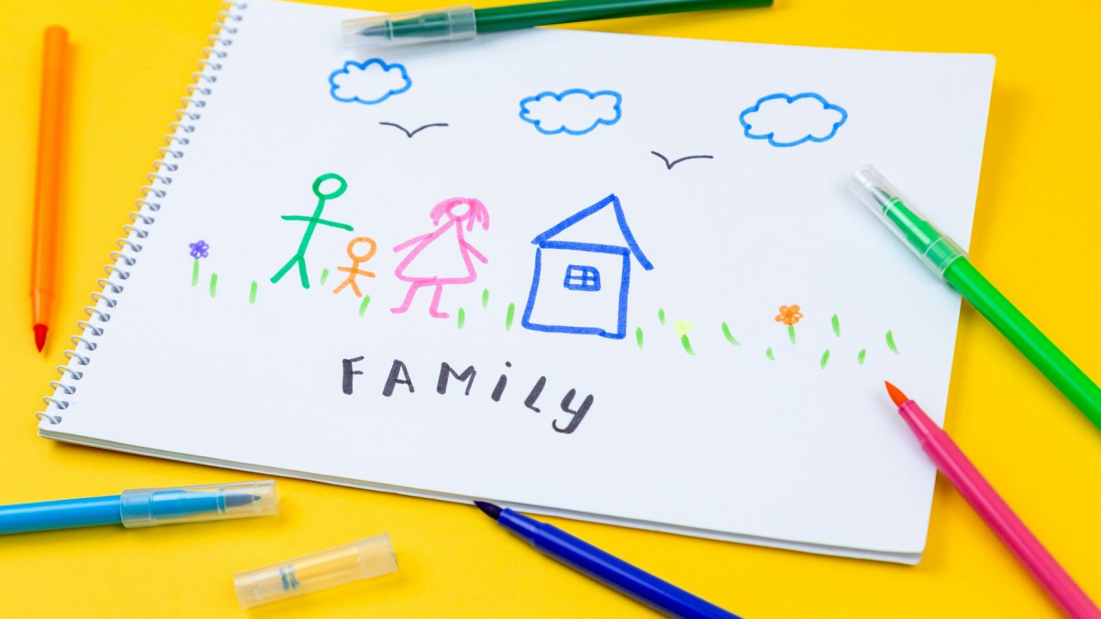 Filzstift liegt auf einer bunten Kinderzeichnung, die eine Familie zeigt