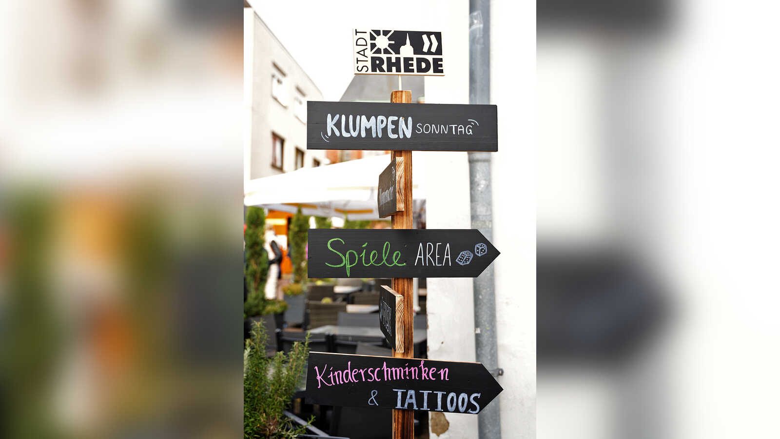 Holzwegweiser mit Schildern Klumpensonntag, Spiele-Area und Kinderschminken in der Rheder Innenstadt