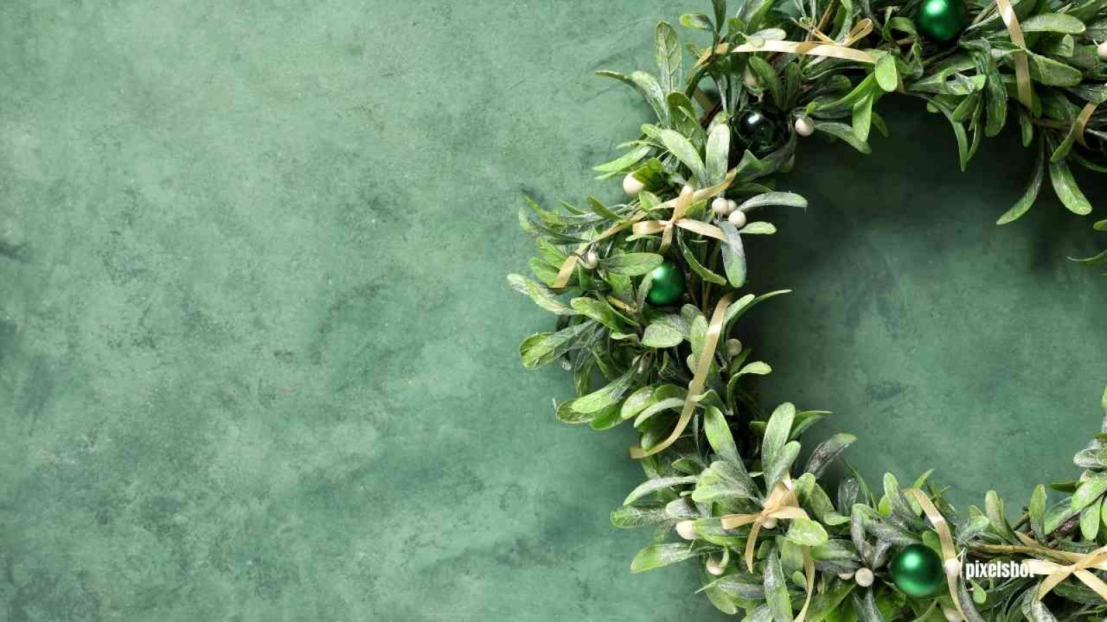 Grüner Kranz aus Blättern und kleinen grünen Kugeln auf einem strukturierten Hintergrund.