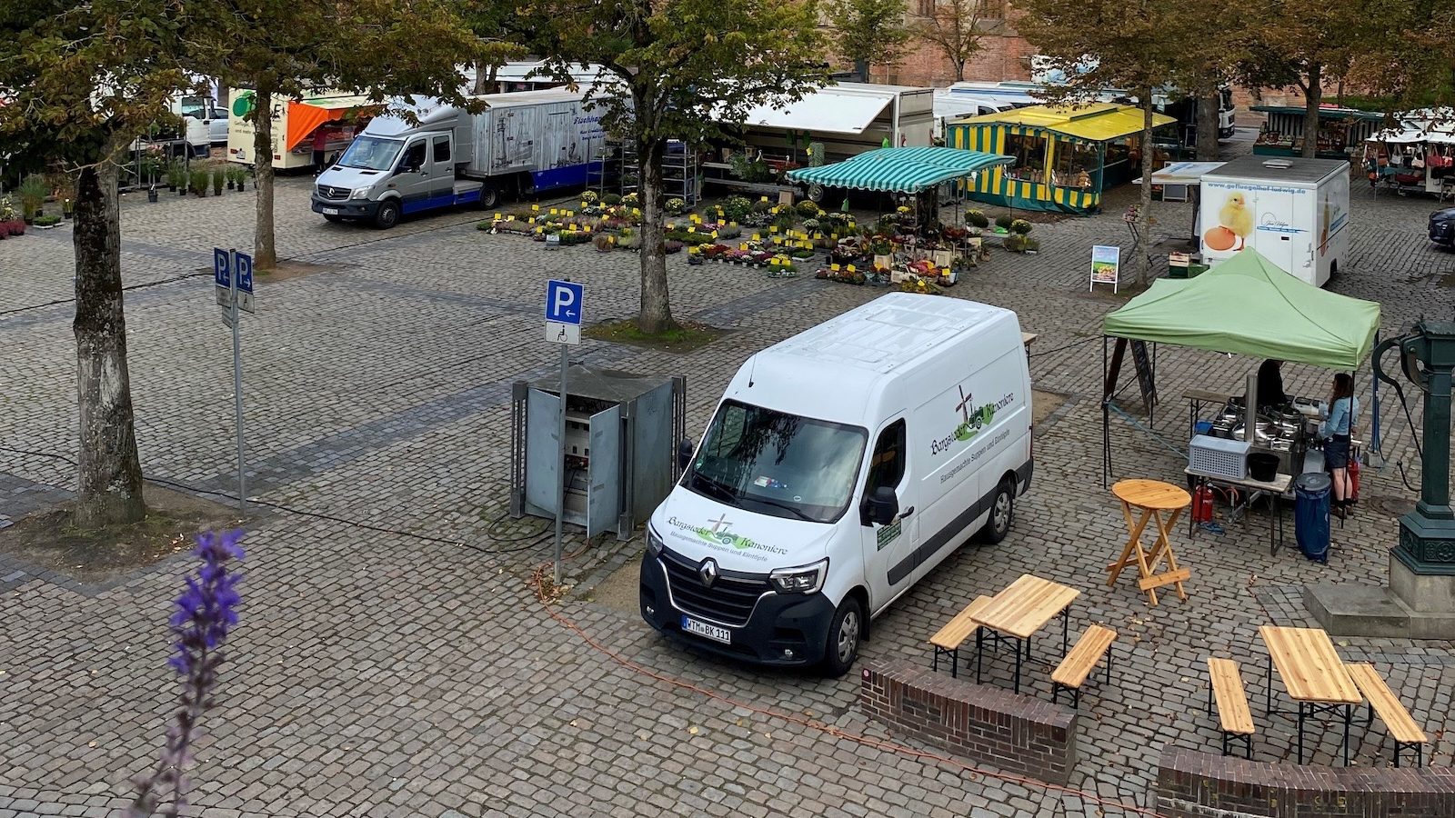 Marktstände und Verkaufswagen auf dem baumbestandenen Marktplatz in Norden, im Hintergrund die Ludgerikirche