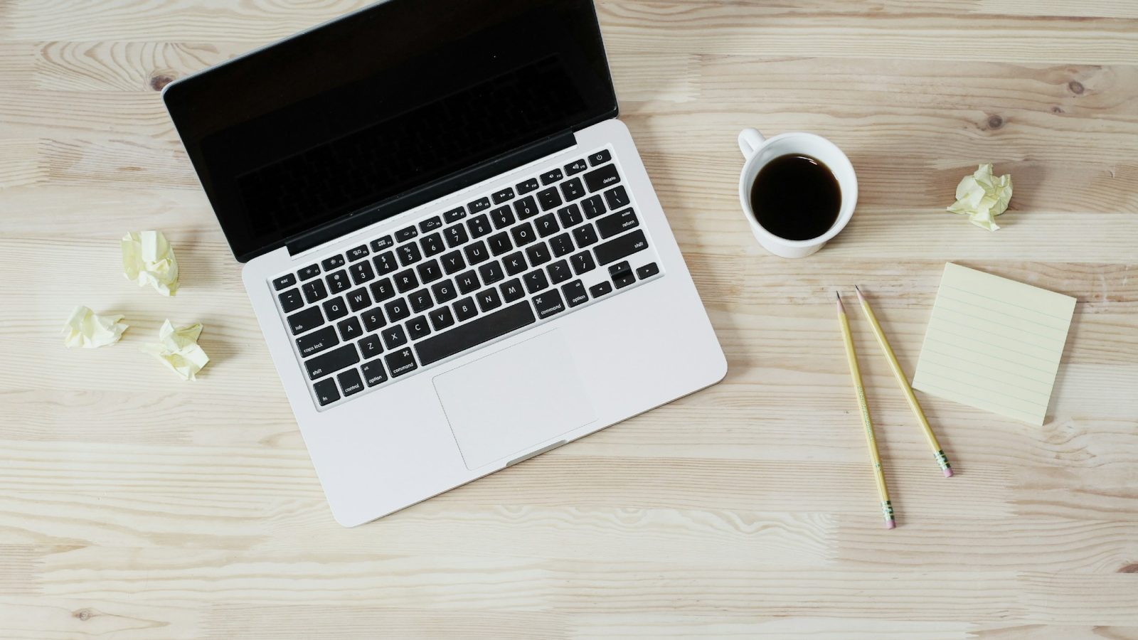 Notizbuch, Laptop und Kaffee auf einem Schreibtisch
