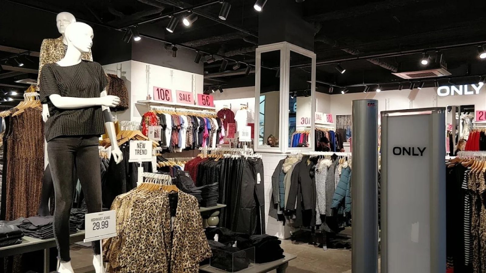 Modegeschäft Innenansicht mit Schaufensterpuppen, Kleidung auf Kleiderständern und SALE-Schildern.