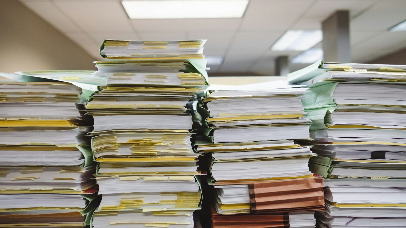 Stapel von Papierdokumenten und Aktenmappen in einem Büro