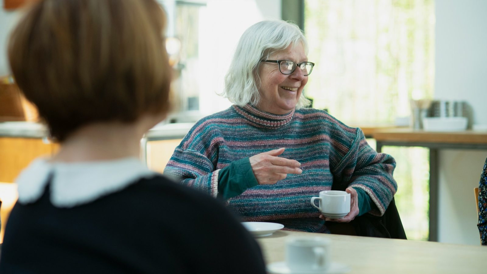Zwei Frauen sitzen im Gespräch an einem Tisch