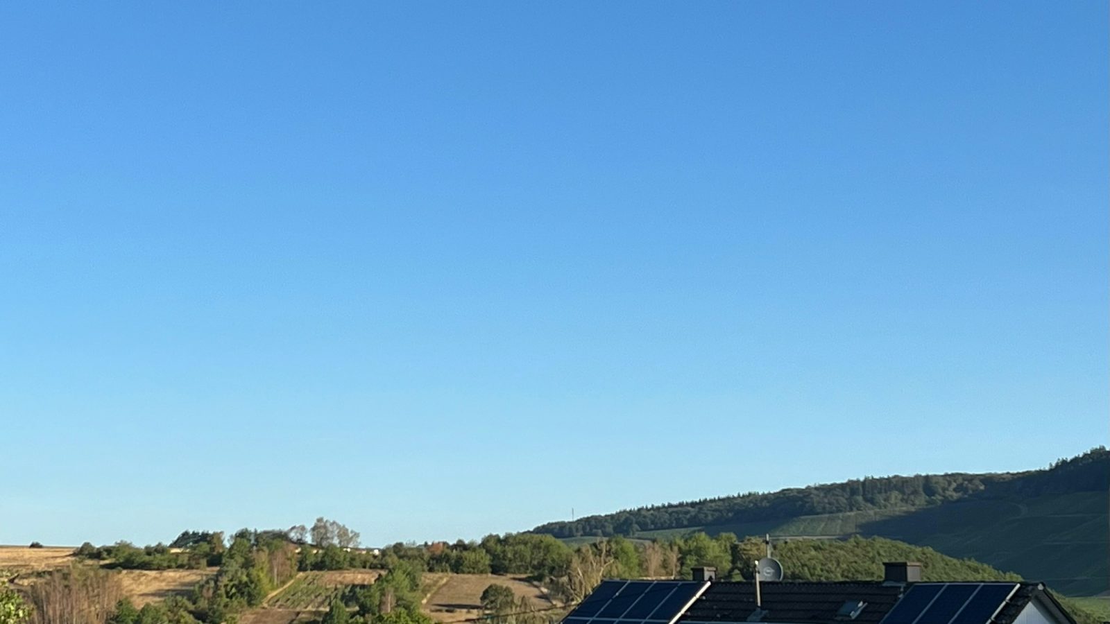Solarmodule auf einem Hausdach unter blauem Himmel