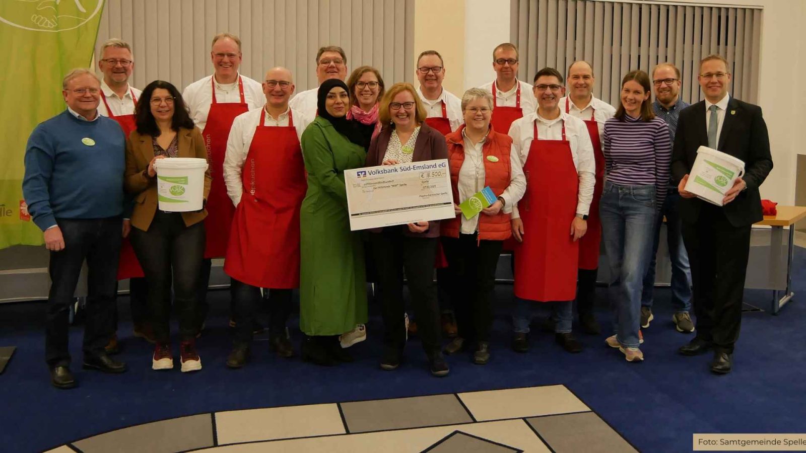 Die Piepkuchenbäcker (mit roten Schürzen, von links) Andreas Robin, Martin Rekers, Andreas Brüggemann, Stefan Heeke, Andreas Teders, Ludger Schröer, Reiner Baltes und Klaus Sändker übergeben die Spende an den Hilfsfonds WIR in der Samtgemeinde Spelle.