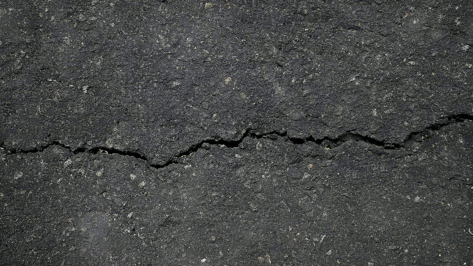 Rissiger Asphalt auf einer Straße, Symbolbild für Fahrbahnschäden