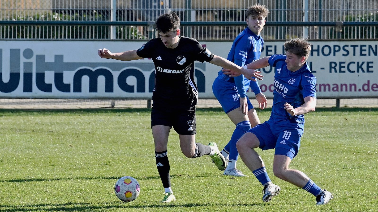Niklas Oswald vom SC Spelle-Venhaus setzt sich im Testspiel gegen Eintracht Rheine gegen zwei Gegenspieler durch