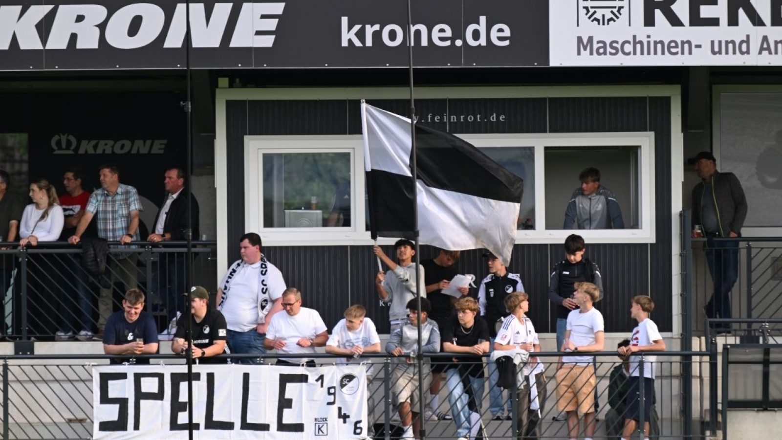 Fußballfans auf der Tribüne mit Banner und Flagge, zeigen ihre Unterstützung beim Spiel in Spelle.