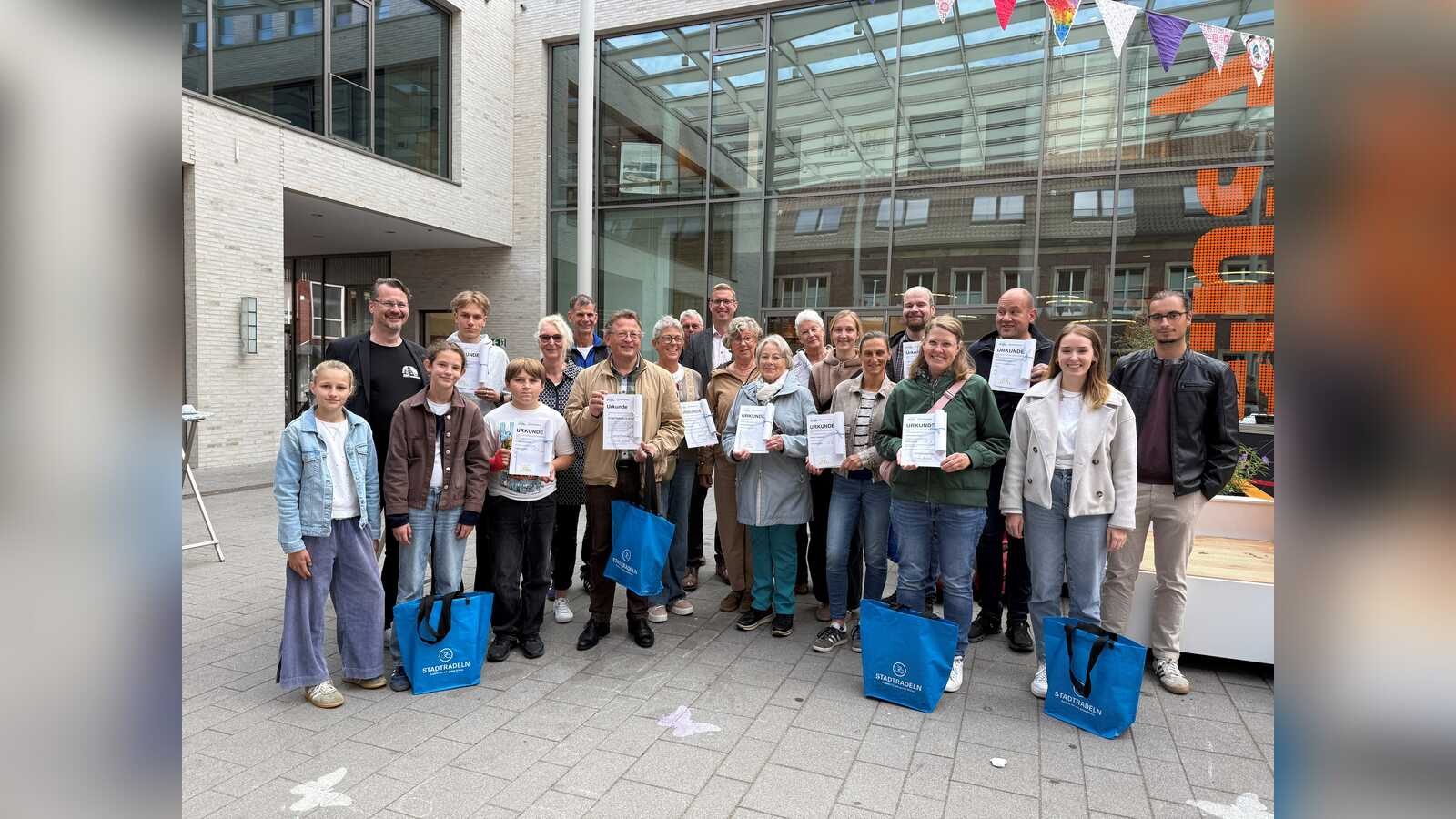 Gruppenfoto der Preisträgerinnen und Preisträger von STADTRADELN Dülmen 2026 mit Urkunden und blauen Stadtradeln-Taschen vor dem Rathaus