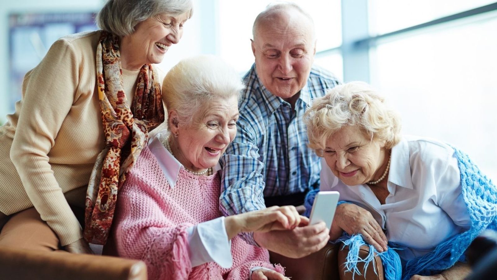 Ältere Menschen lachen, während sie gemeinsam auf ein Smartphone schauen, genießen Technologie und soziale Verbindung.