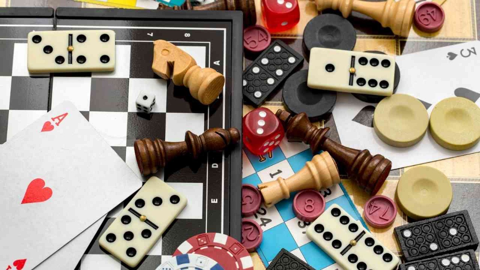 Spieleabend: Verschiedene Spielsteine, Karten und Würfel auf einem Tisch, Symbol für Brett- und Kartenspielvielfalt.