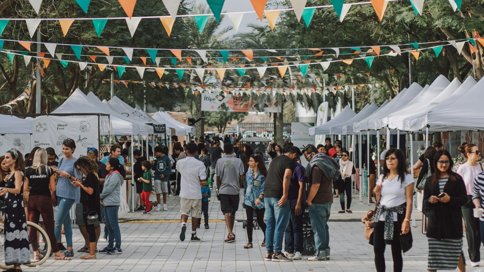 Besucher gehen bei einem Straßenfest zwischen Zelten und Ständen entlang