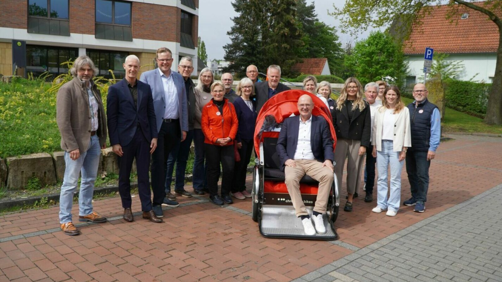 Landrat Uwe Fietzek (sitzend in der Rikscha), Sozialdezernent Gert Lödden (3.v.l.), Stabsstellenleiterin Mareike Bölle (5.v.r.) und Stabsstellenmitarbeiterin Christine Deters (2.v.r.) starteten mit Günter Behrendt (10.v.l.), den Ehrenamtlichen des Rikscha-Projektes sowie den Sponsoren in die neue Rikscha-Saison. (Landkreis Grafschaft Bentheim)