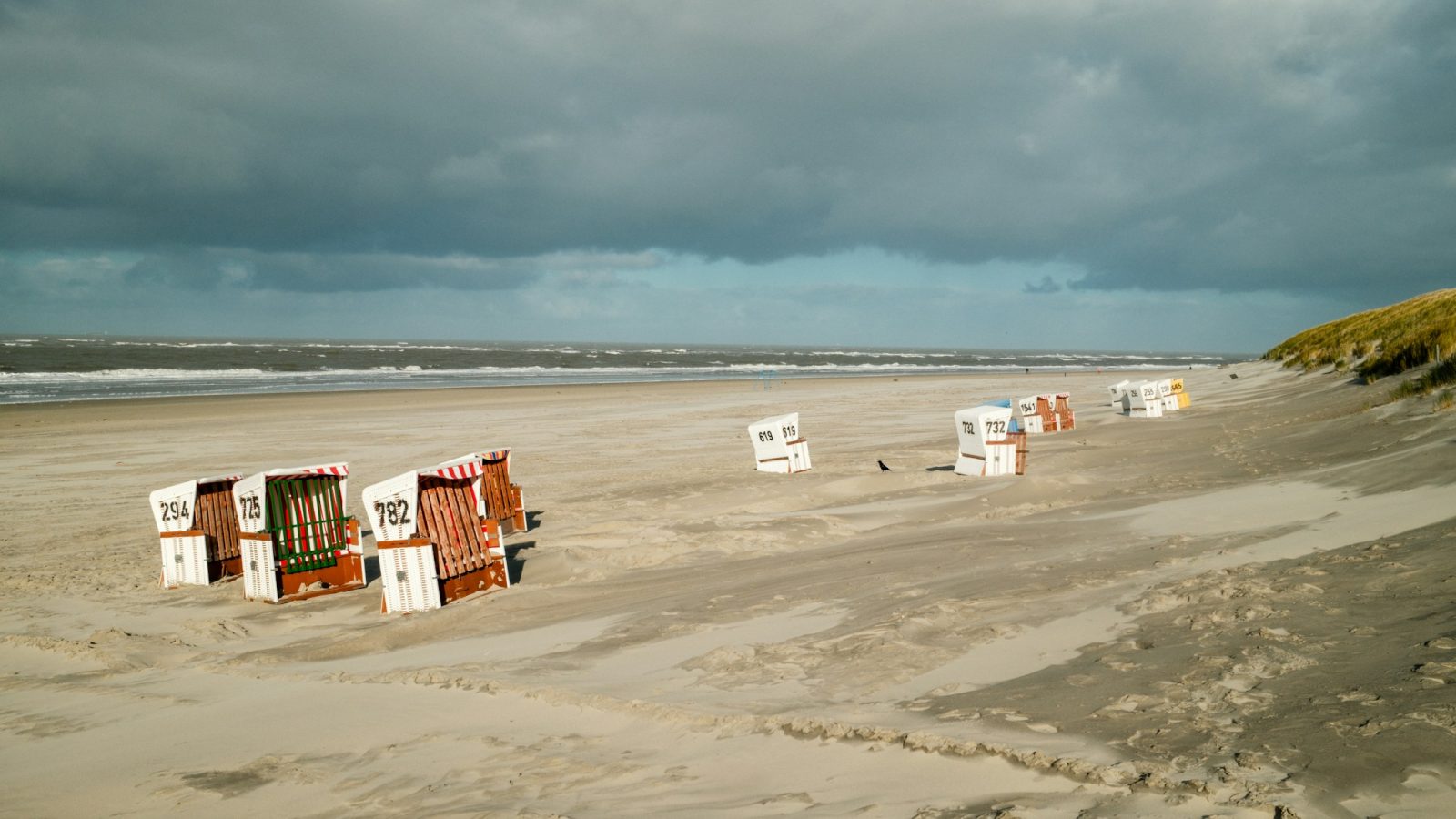 Strandkörbe an einem Sandstrand an der Nordsee unter bewölktem Himmel