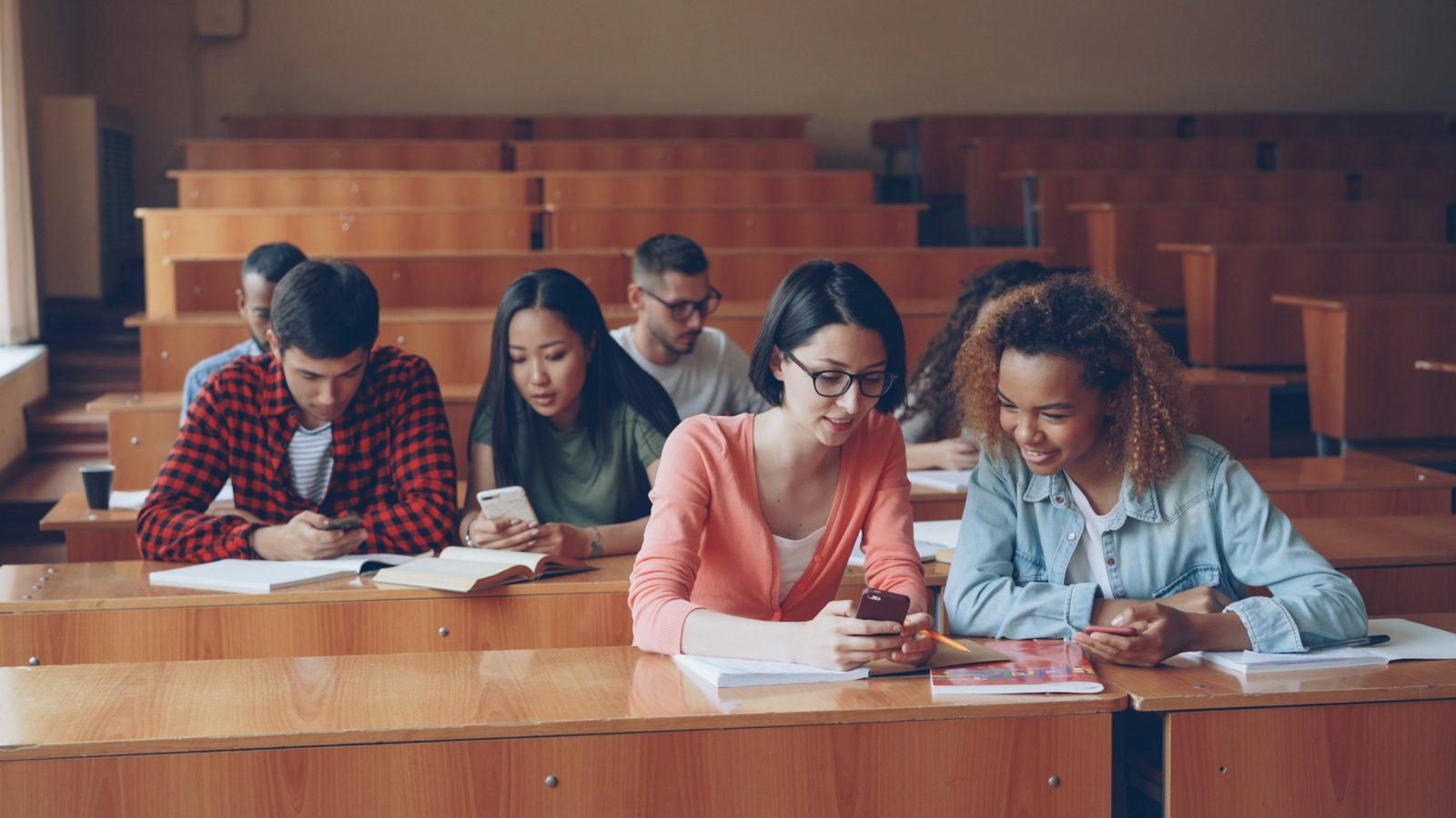 Studierende sitzen an Tischen in einem hellen Hörsaal