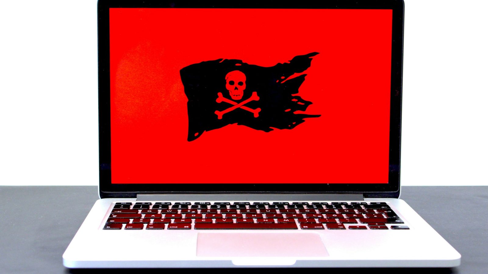 Laptop mit Totenkopf-Symbol auf rotem Bildschirm als Zeichen für einen Hackerangriff