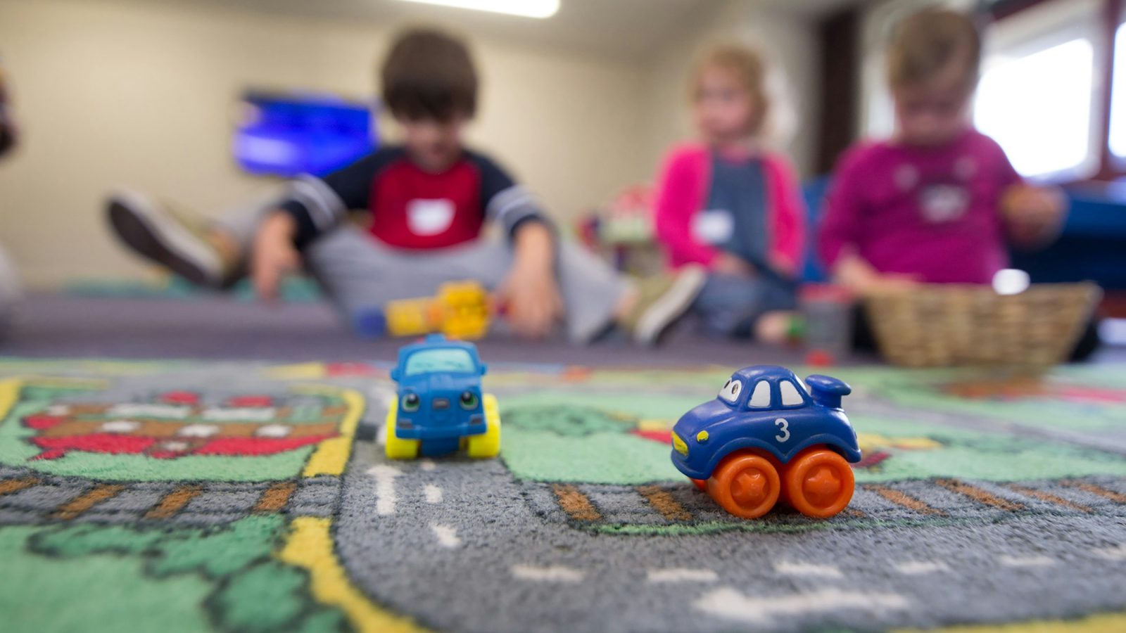 Spielzeugautos auf einem Straßen-Spielteppich in einer Kindertageseinrichtung