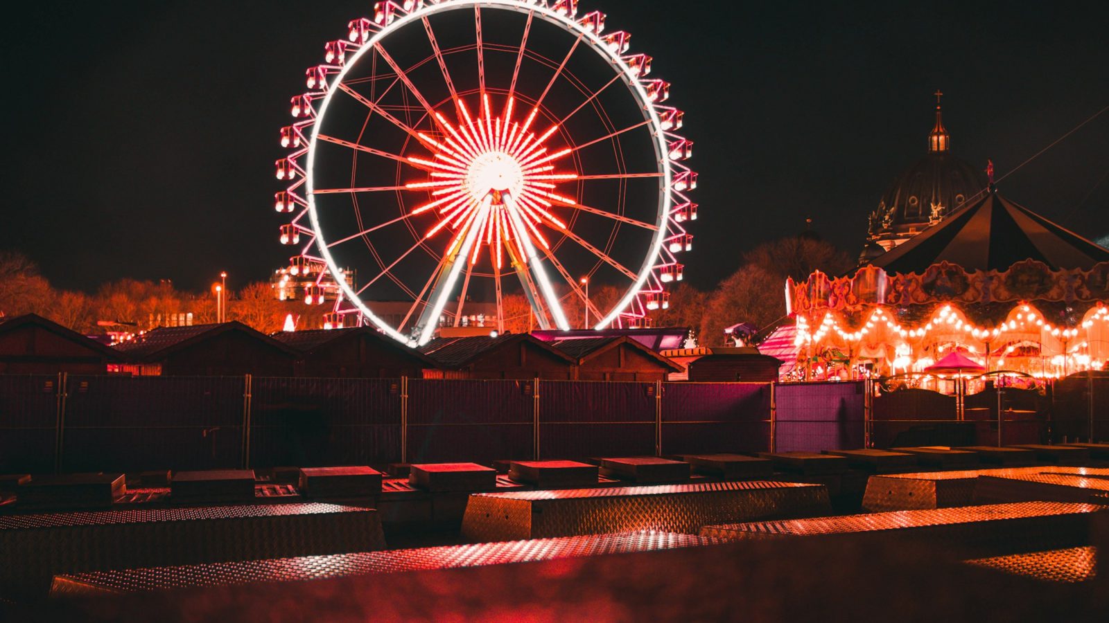 Beleuchtetes Riesenrad und Karussell auf einem Rummelplatz bei Nacht als Symbolbild für die Dreifaltigkeitskirmes Dülmen