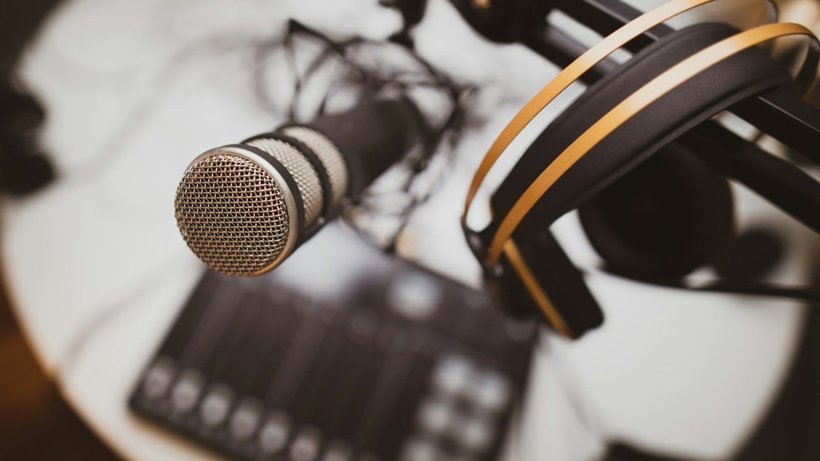 Podcast-Mikrofon und Kopfhörer auf einem Schreibtisch (Symbolbild)