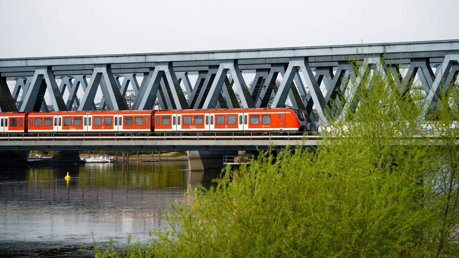 Regionalzug überquert eine Stahlbrücke über einen Fluss (Symbolbild)