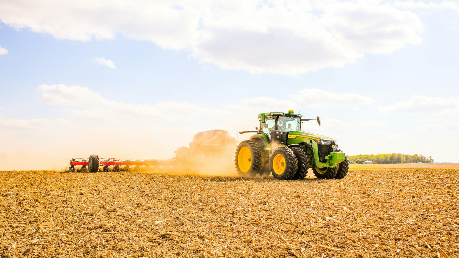 Traktor mit Anhänger bei der Feldarbeit auf einem Acker (Symbolbild)