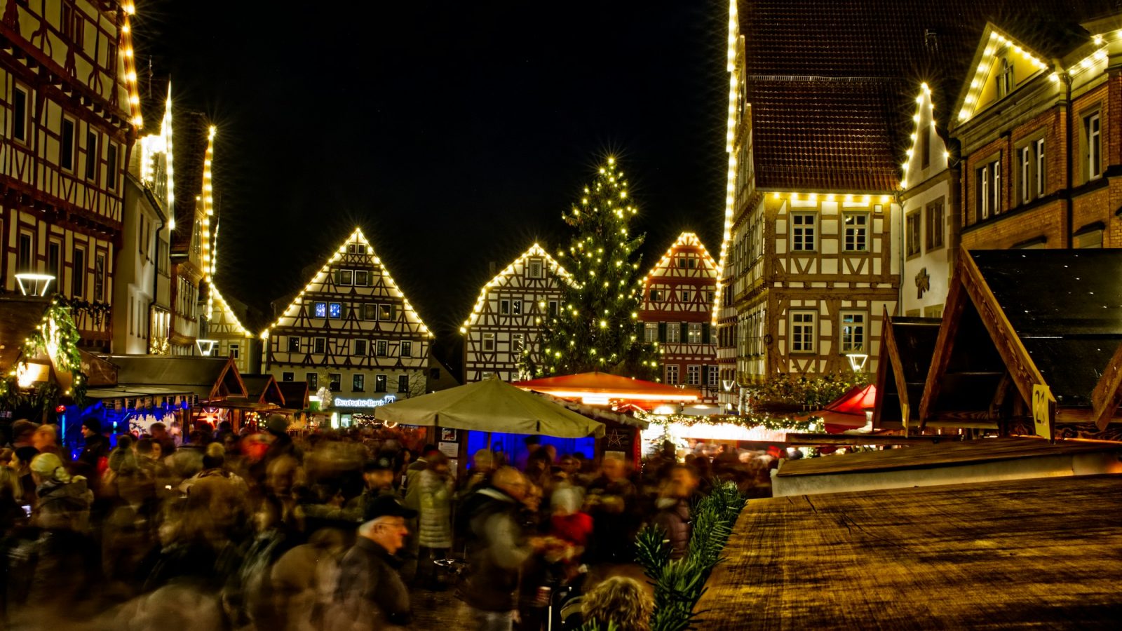 Beleuchtete Holzbuden auf einem Weihnachtsmarkt am Abend